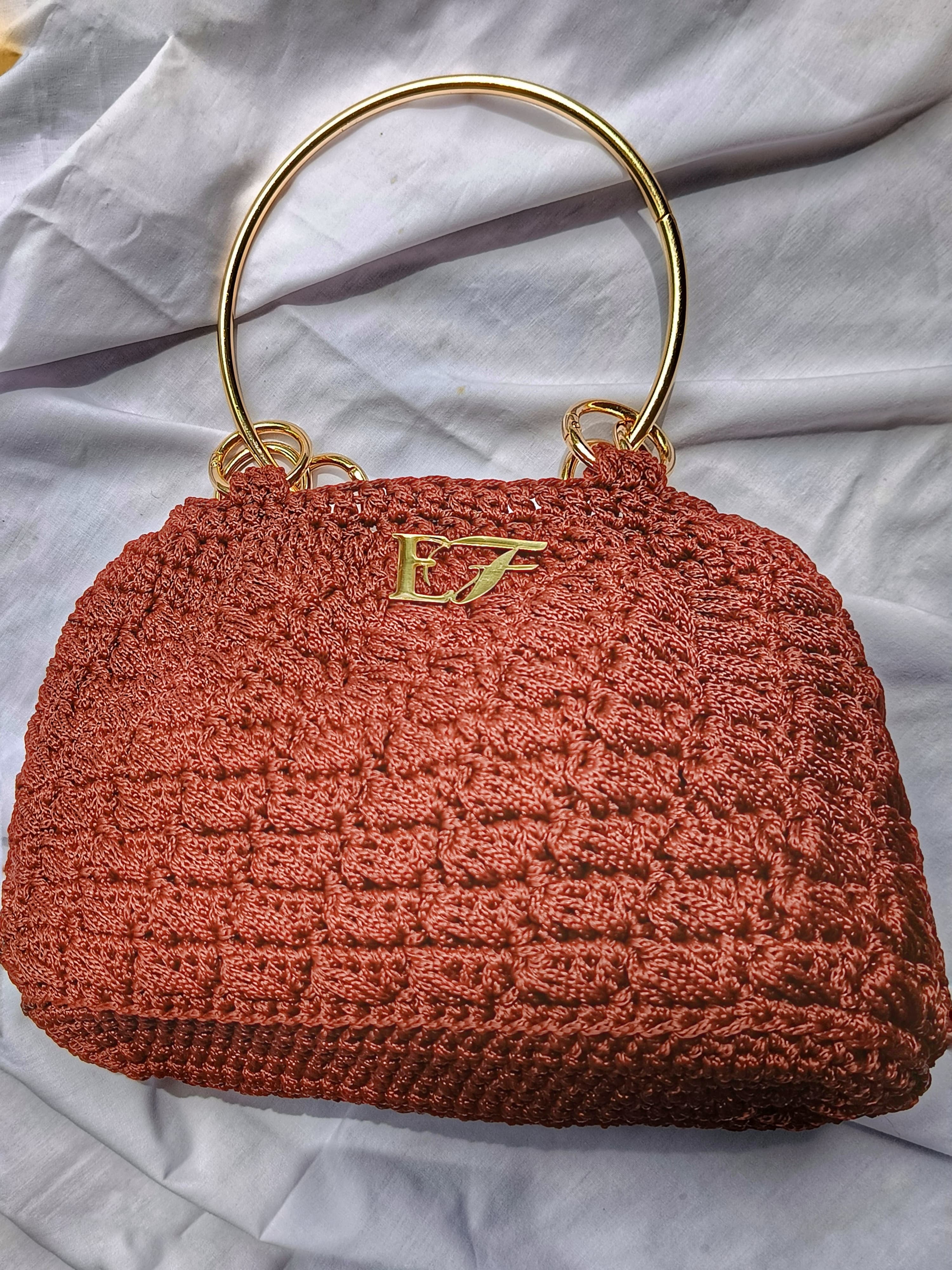 Rust-colored crochet handbag with ring handle and EF emblem.